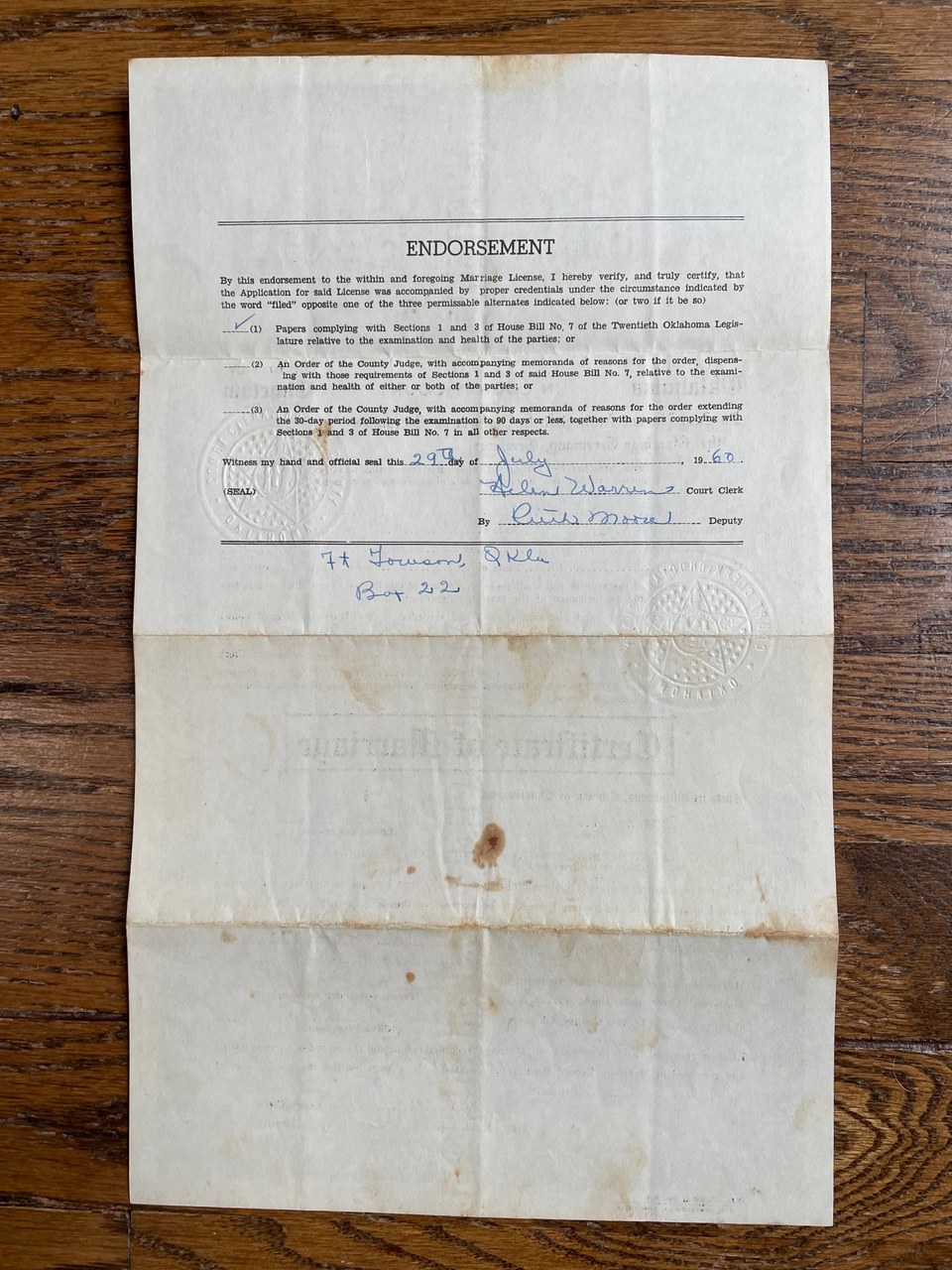 Aged legal endorsement document with handwritten signatures and county seal on wooden surface.