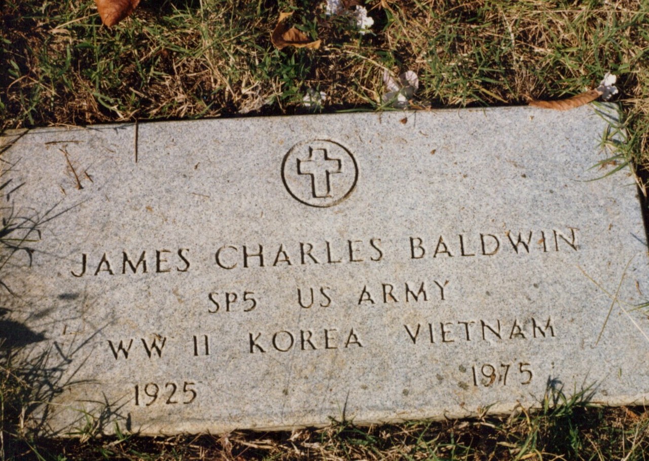 Flat granite U.S. military grave marker for James Charles Baldwin, SP5 US Army, veteran of WWII, Korea, and Vietnam, 1925–1975, with an engraved cross in a circle at the top