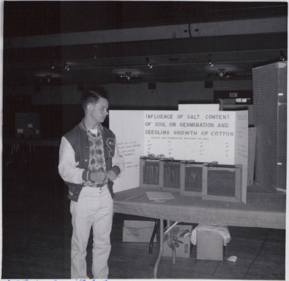 Man presenting cotton salt-content research display indoors