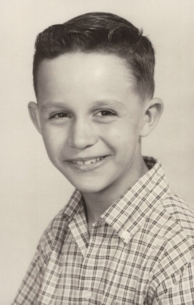 Black and white portrait of a young boy smiling at the camera.