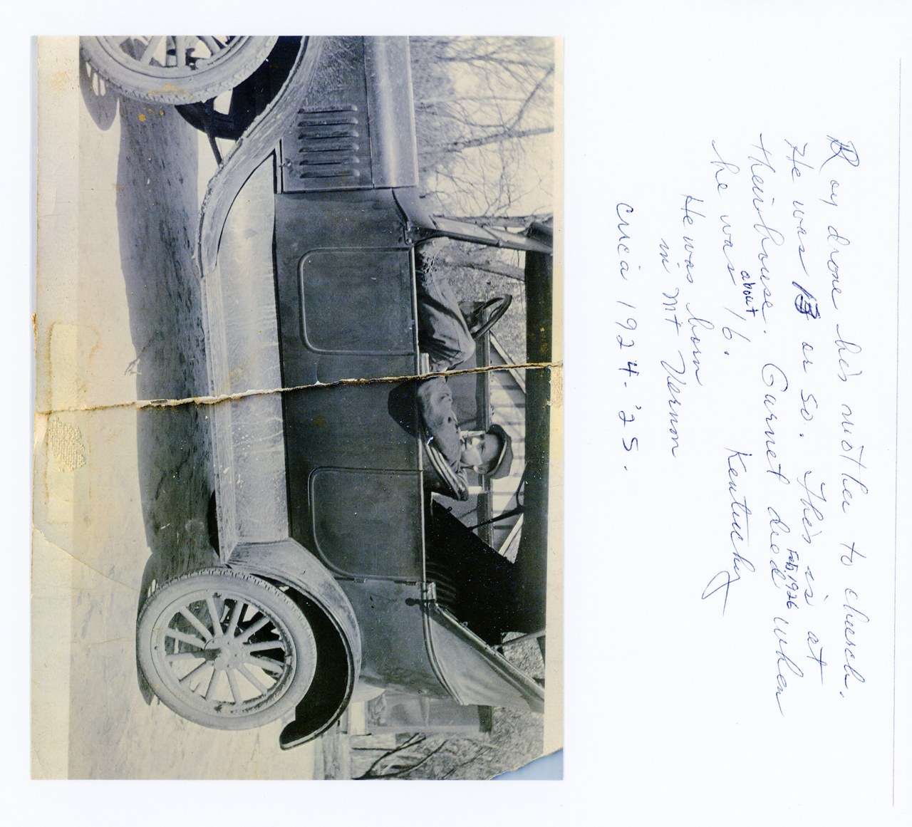Person sitting in driver's seat of vintage automobile, rotated view.