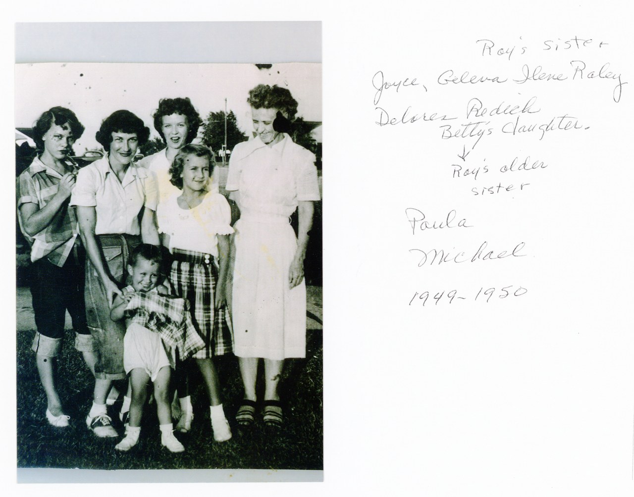 Family group photo of seven women and girls posed together, black and white