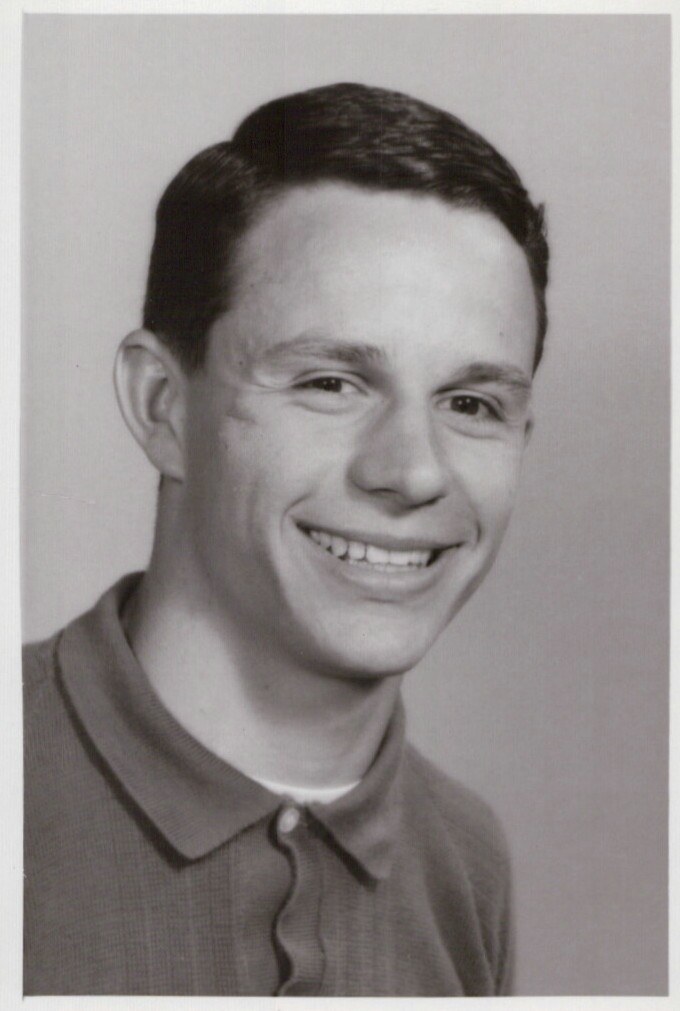 Black and white portrait photograph of a smiling man against a plain background.