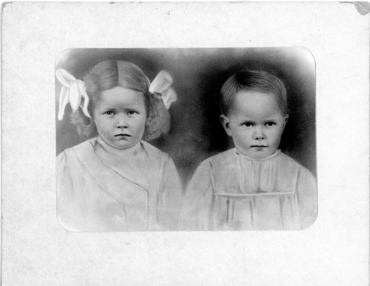 Two young children in early 20th century clothing, formal studio portrait